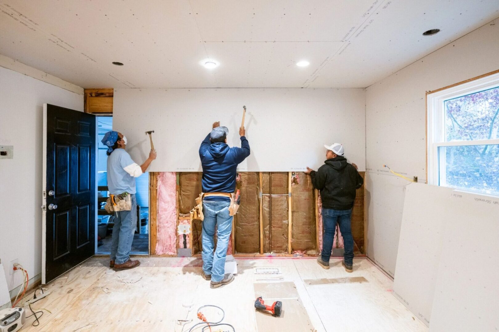 Construction workers installing drywall in room